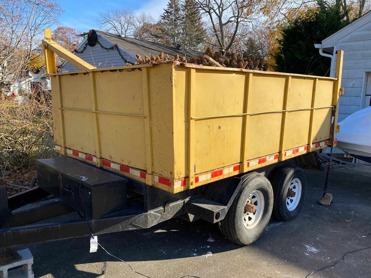 A portable rubbish dumpster on a trailer parked in a residential driveway